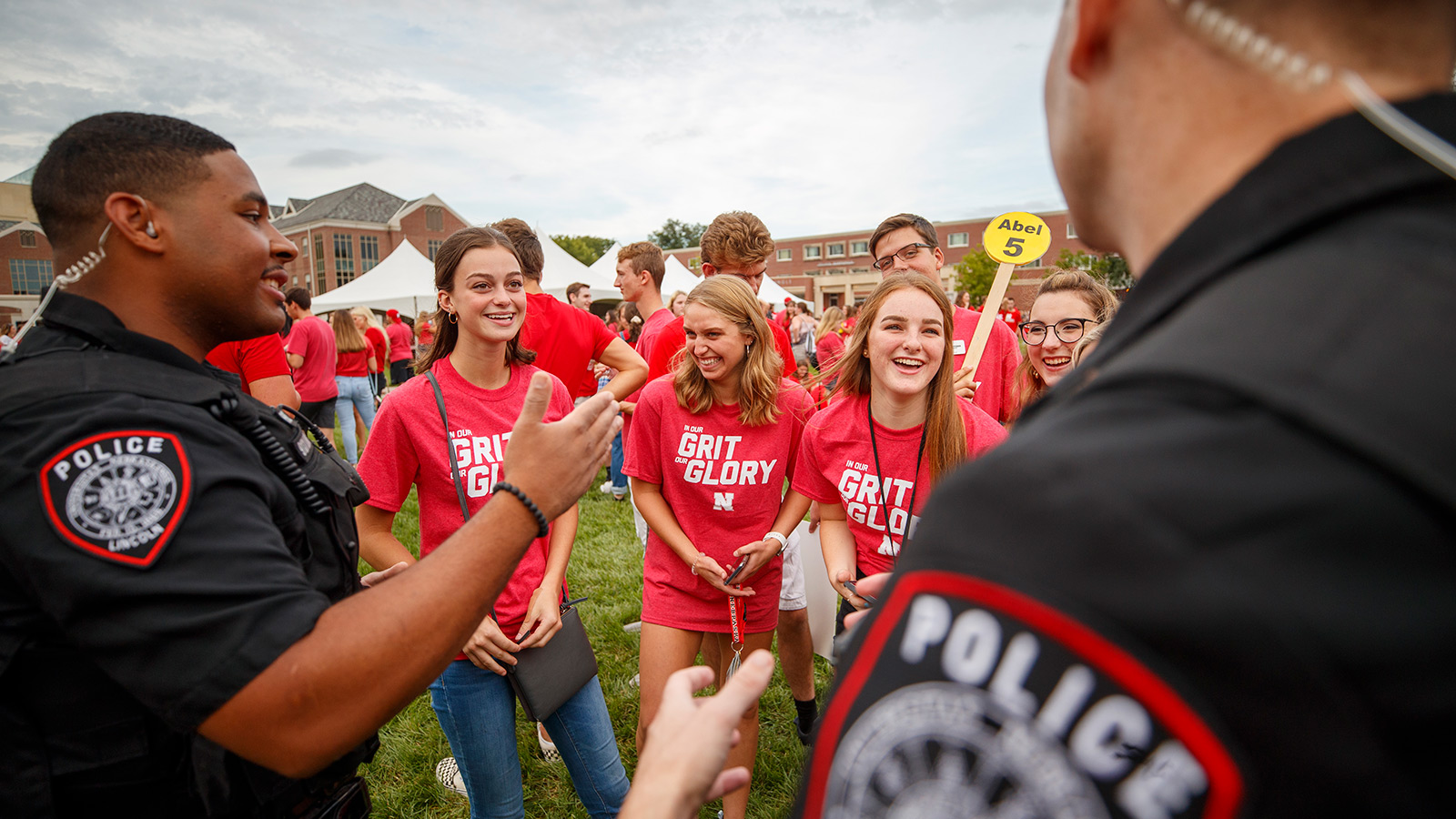 Two police officers talk to a group of students during a picnic on the Green space on campus.