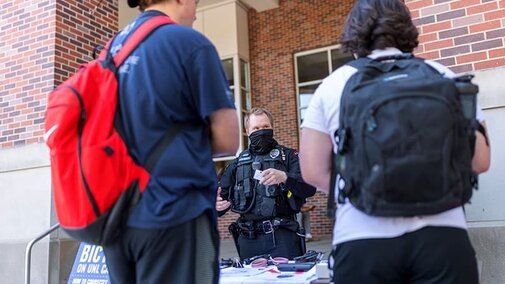 Two students stand in front of Police informational table.