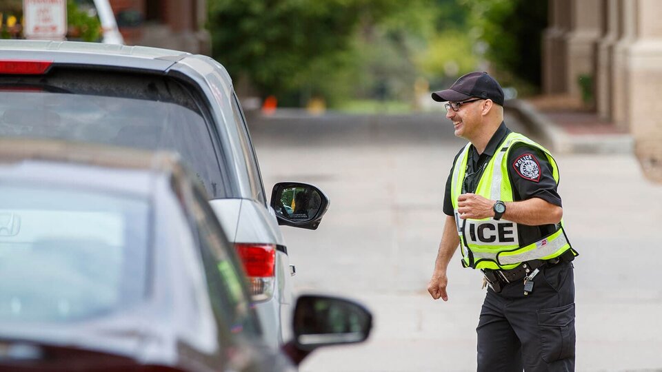 An officer smiles as the direct a car full of students