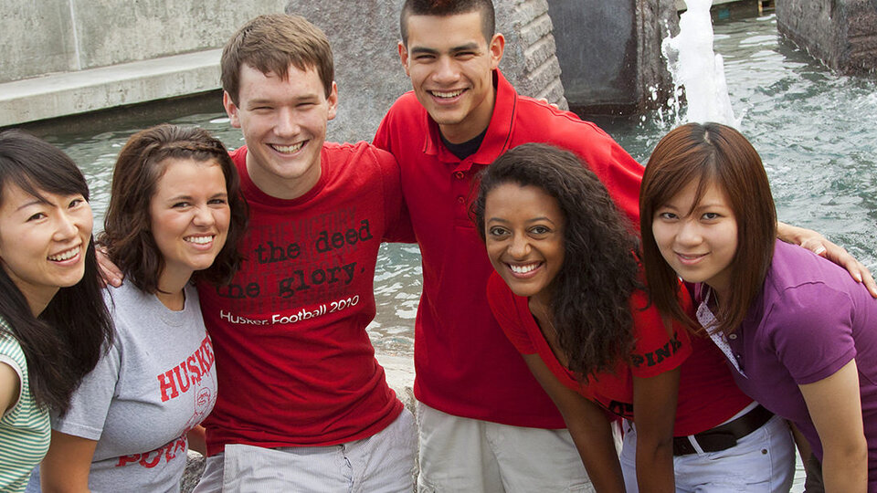 Students standing in fountain smiling for camera.