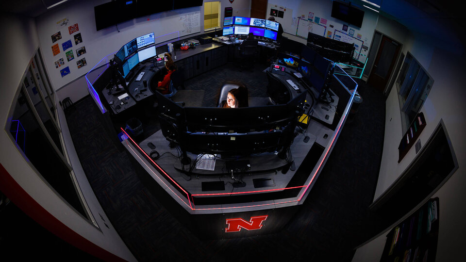 Police dispatcher in room surrounded by monitors and communication devices