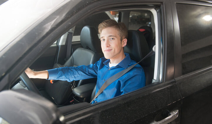 Student sits in the drivers seat of a car.